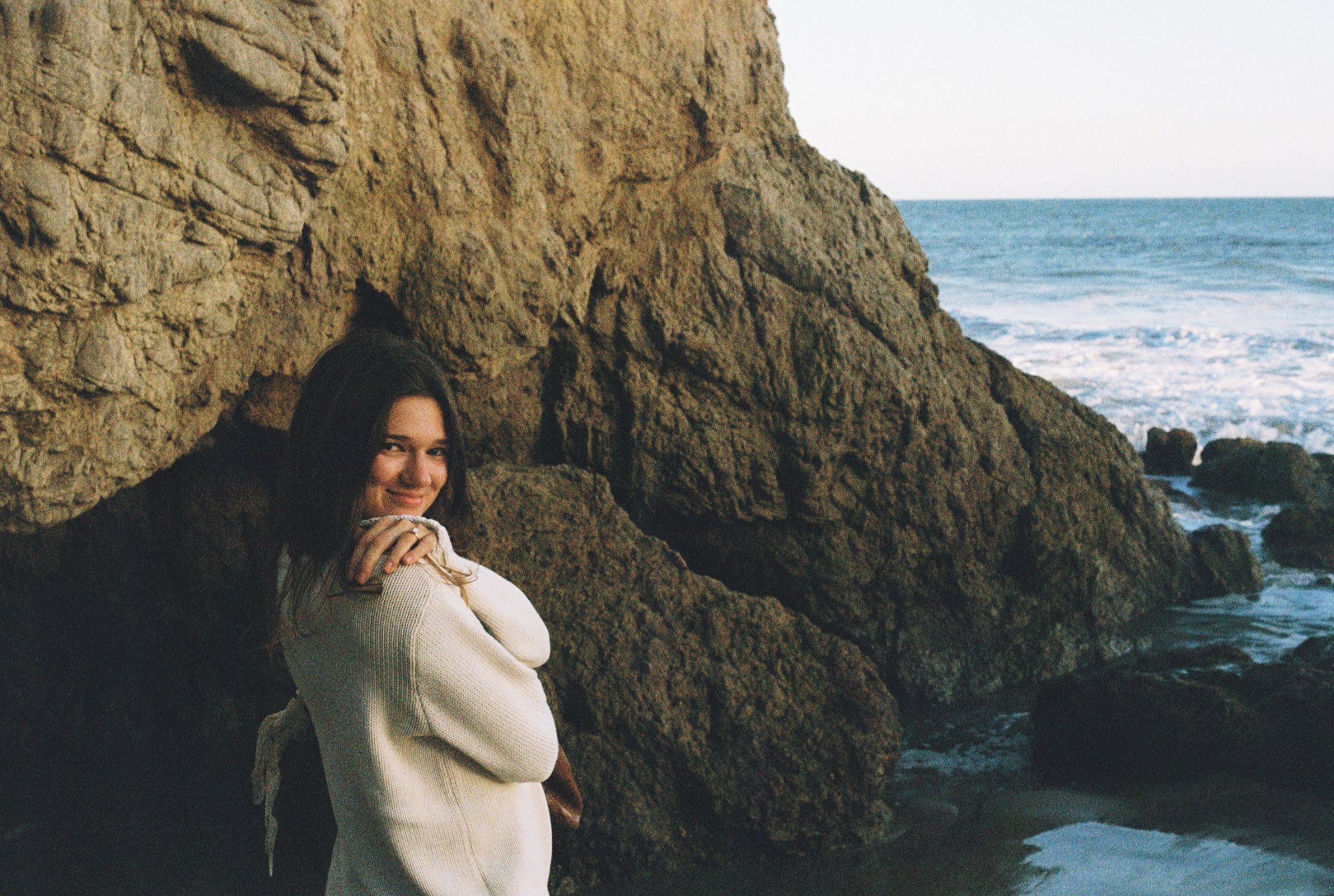 Grace against the rock face at El Matador with the surf beyond.