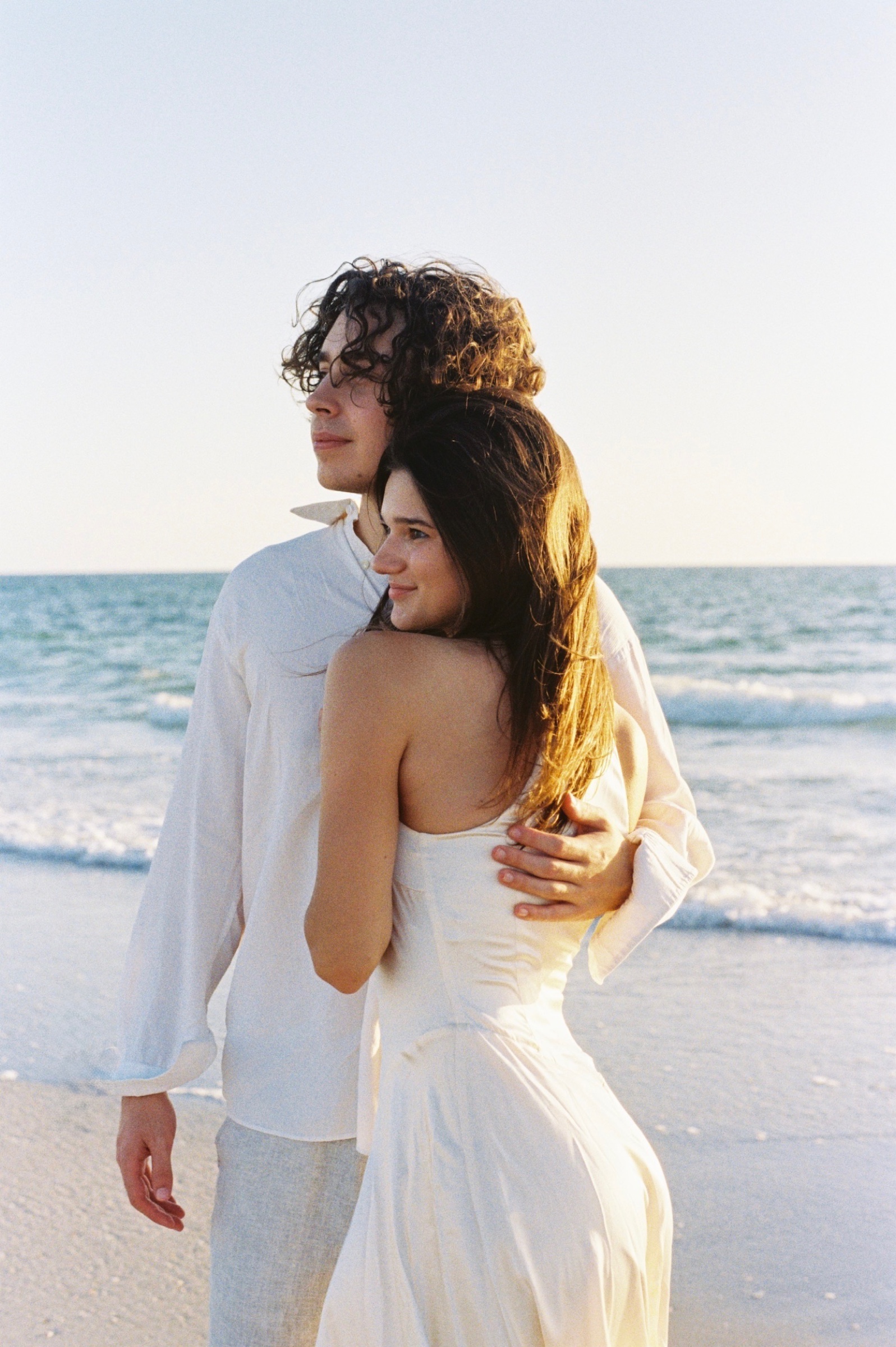 Grace and Christian embracing on Pass-a-Grille Beach at golden hour.