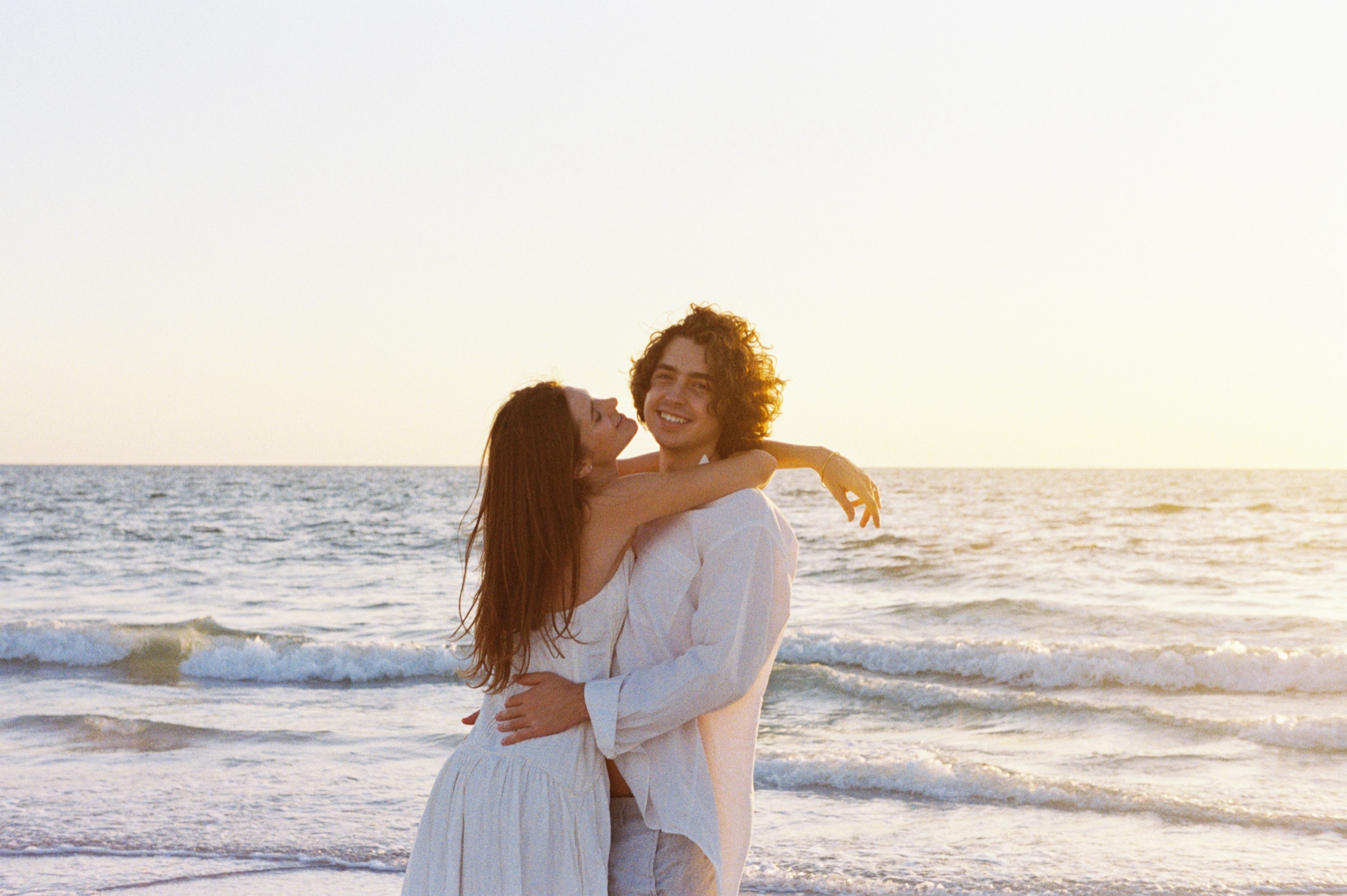Grace wrapping her arms around Christian at the water's edge.
